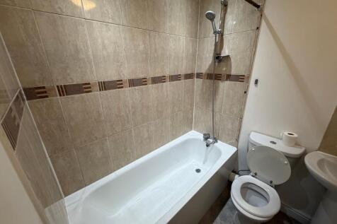 Clean, neutral-tiled bathroom with a white bath...