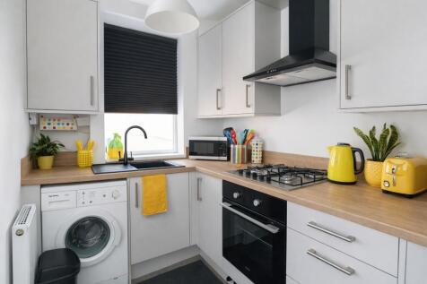 Bright, modern kitchen with white cabinetry, wo...