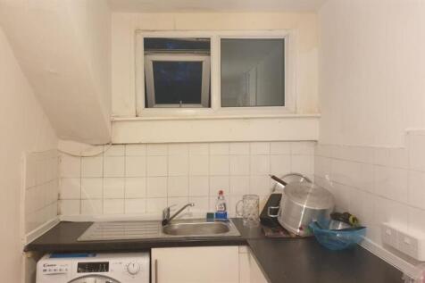 Compact fitted kitchen with white tiled splashb...