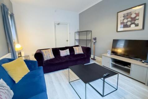 Bright living room with modern sofas and TV...