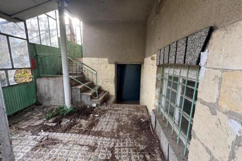 Covered entrance showing patterned tiled floor, stairs leading to upper and lower levels, and barred windows