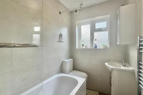 Modern tiled bathroom suite with bath and windo...