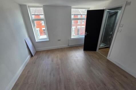 Bright master bedroom with sleek wood flooring...