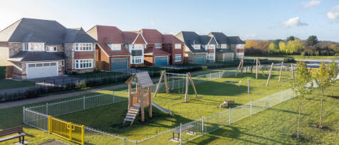 Modern houses with coloured roofs and a children¿s playground enclosed by a white fence in a suburba
