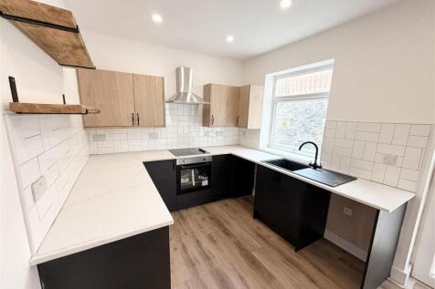 Modern kitchen with sleek dark units and window...