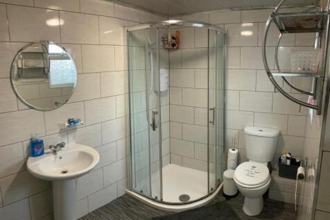 Bright, modern bathroom with a curved glass sho...