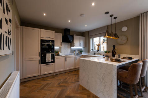 A modern kitchen with a marble island and bar stools in the foreground