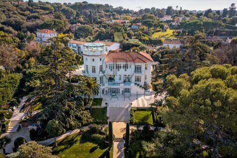 Aerial view of a luxurious white mansion surrounde