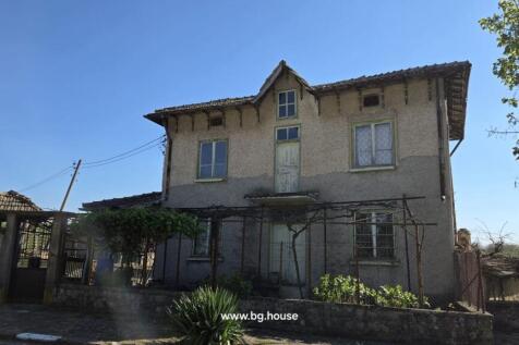 Front view of a two-storey Bulgarian house with textured walls and several windows.