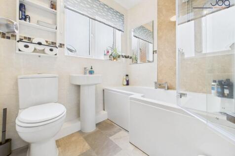 A white three-piece suite, including a P-shaped shower bath with overhead shower.