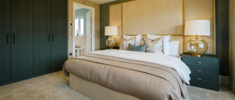 Modern bedroom with green wardrobes, beige headboard, white bedding, and two glass table lamps on te