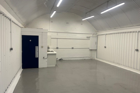 An empty arch with white lining and a WC cubicle to the back.