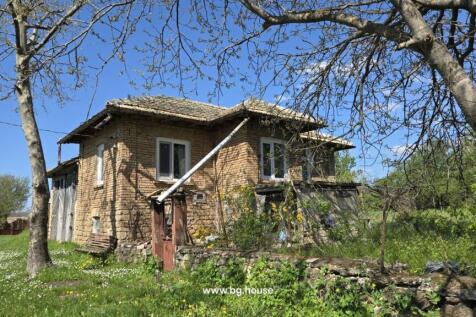 View of the old brick house with a tiled roof and garden area with trees and grass