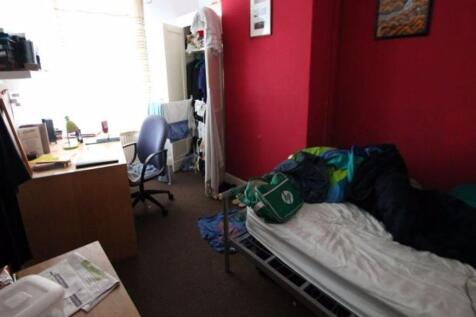 A cozy single bedroom featuring a desk by a lar...