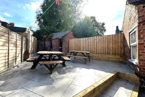 Spacious paved garden with social picnic seatin...