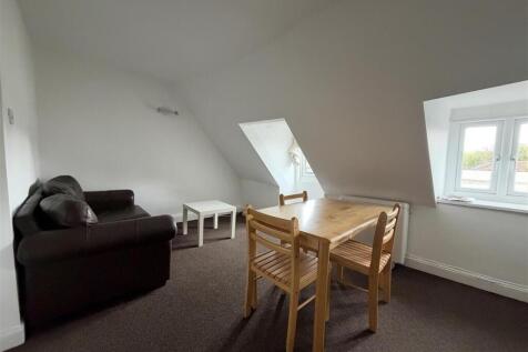 Bright attic living area with sofa and dining s...