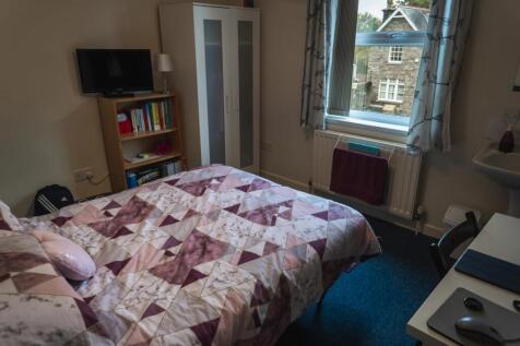 A cozy double bedroom featuring a patterned bed...