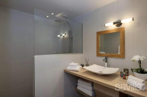 A modern bathroom with a glass shower, a wooden co