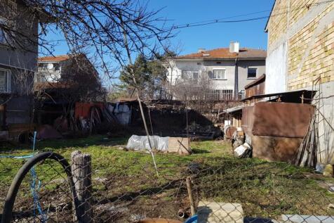 View of fenced grassy building land with garden structures and bare trees in Popovo, Bulgaria