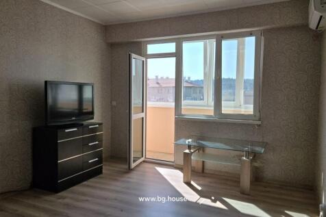 Spacious living room showing a TV on a black chest of drawers, a glass coffee table, and an open door to the balcony.