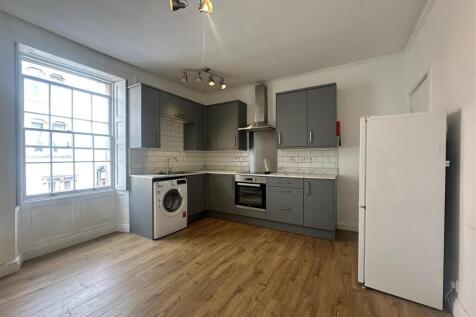 Modern kitchen with sleek units and bright wind...
