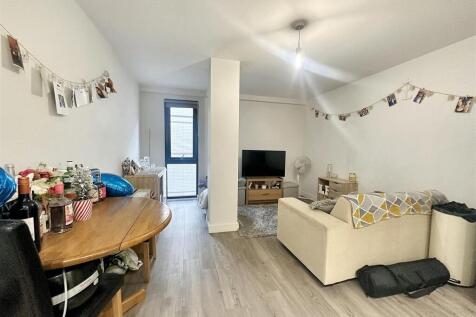 Bright, open-plan lounge with cozy sofa and TV...