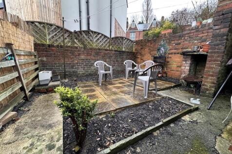 Enclosed paved rear garden with a central patio...
