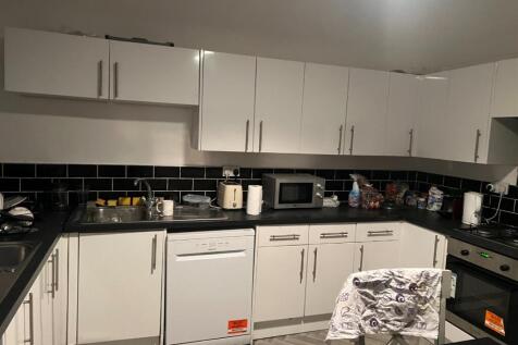 Modern fitted kitchen with white cabinetry, bla...