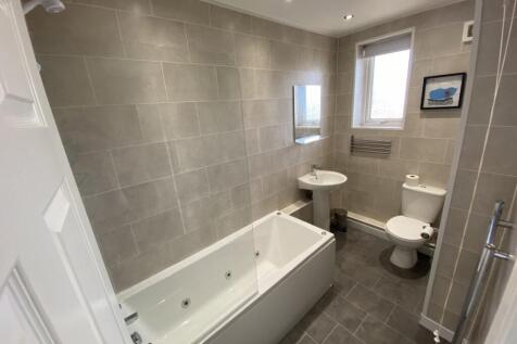 A spacious and modern bathroom featuring a rela...