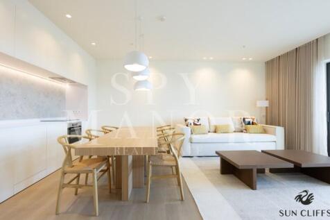 Open plan dining area at Sun Cliffs Resort, Lagos, featuring a wooden table, modern chairs, and a luxury integrated kitchen.