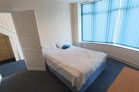 Bright bedroom featuring a large bay window...