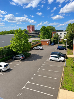 Sunny Parking Lot Overlooking City Buildings.png