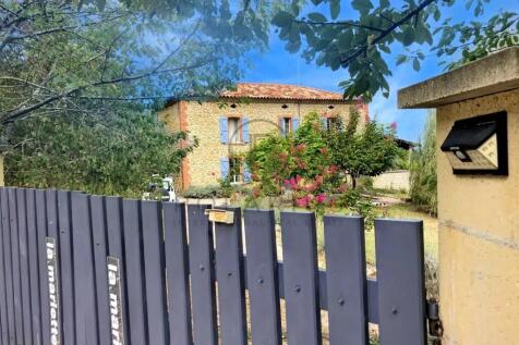 A rustic stone house with blue shutters is seen be