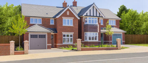 Modern, red-brick detached house with grey roof, white window frames, small front garden, and garage