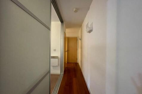 Bright, modern hallway with wood flooring, whit...