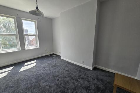 Bright, neutral bedroom with large windows lett...