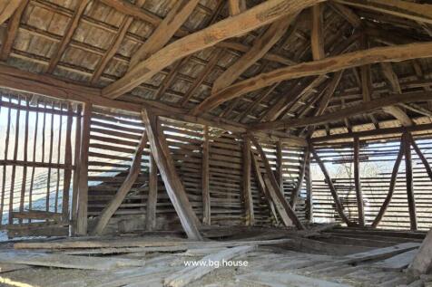Interior view of a barn roof showing wooden beams and slatted walls allowing light inside
