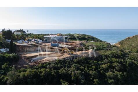 Aerial view of a luxury villa structure under construction on a premium clifftop ridge with panoramic ocean views in Vale de Lapa, Carvoeiro