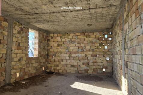 Interior of an unfinished brick room with window openings and concrete ceiling under natural light.