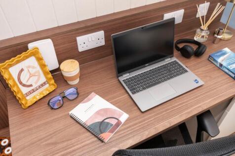 Well-presented wooden desk with a laptop, noteb...