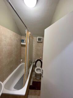 Compact tiled bathroom with a bathtub and showe...