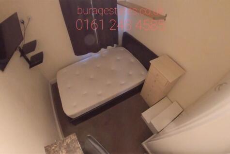 Compact bedroom with a single bed, fitted stora...