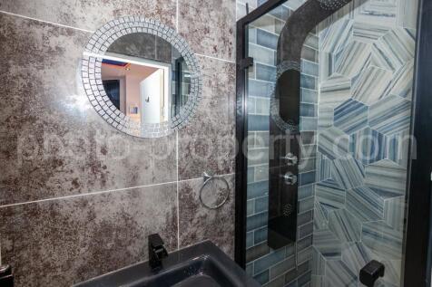 Stylish bathroom with a patterned tiled walk-in...