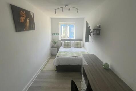 Modern bedroom with a desk and wall-mounted TV...