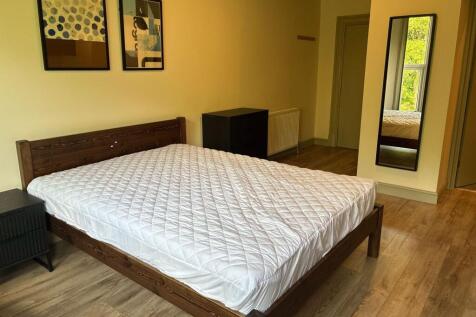 Spacious double bedroom with warm wood floors...