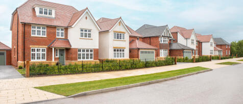 Row of modern detached houses with brick and white facades, red tiled roofs, and small front gardens