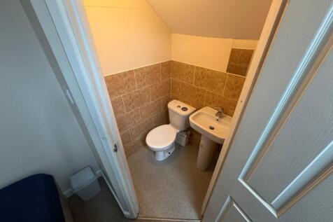 Compact ensuite WC with tiled half-walls, pedes...