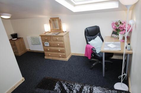 Bright, neatly furnished bedroom with a skyligh...