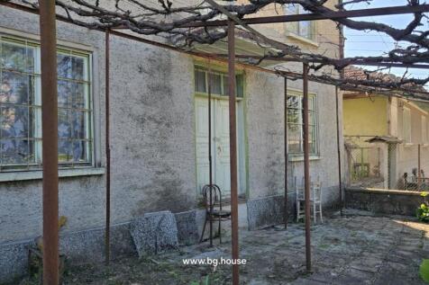 Side entrance of the house with an old wooden door and metal trellis overhead.