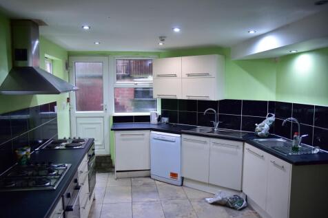 A practical kitchen featuring white cabinetry, ...